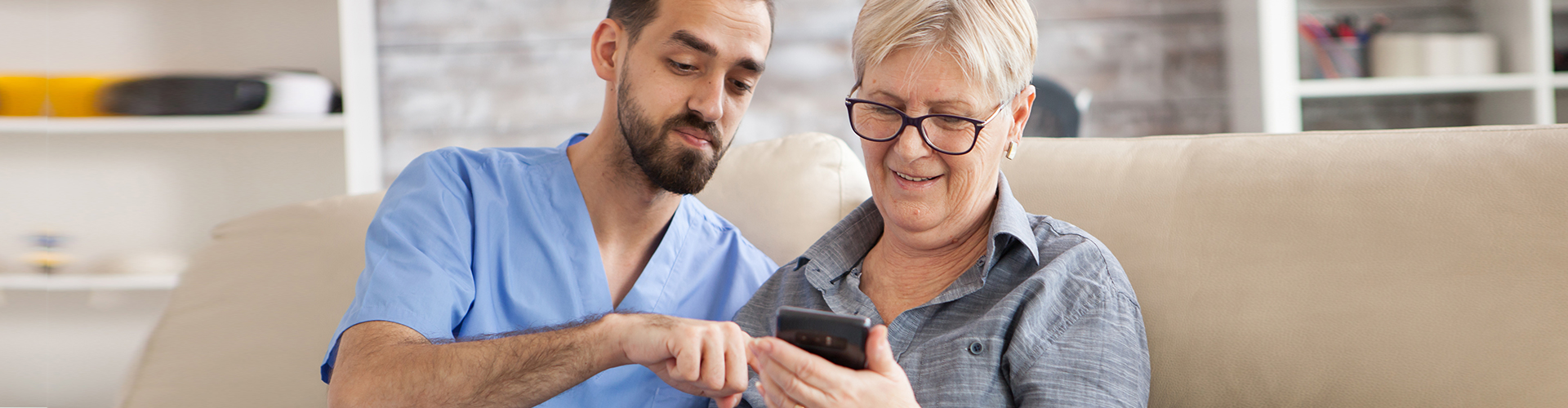 caretaker helping elder woman with phone